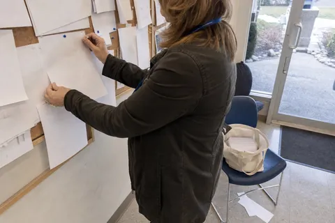 A home care agency manager pinning a printed one-page leaflet to a community noticeboard to build local referrals